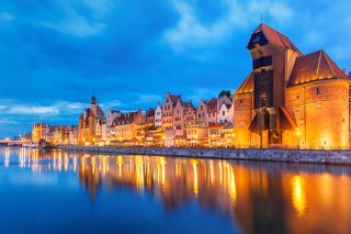 Old harbour crane and city gate Zuraw in old town of Gdansk, Dlugie Pobrzeze and Motlawa River at night, Poland