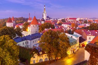 Aerial cityscape with Medieval Old Town, St. Olaf Baptist Church and Tallinn City Wall illuminated in autumn twilight, Tallinn, Estonia