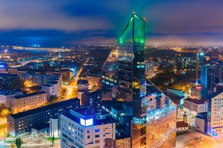 Aerial cityscape of modern business financial district with tall skyscraper buildings illuminated at night, Tallinn, Estonia