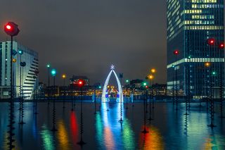 Multicolored fountain and illuminated Arc de Triomphe, view from the Esplanade De La Defense at night in Paris, France