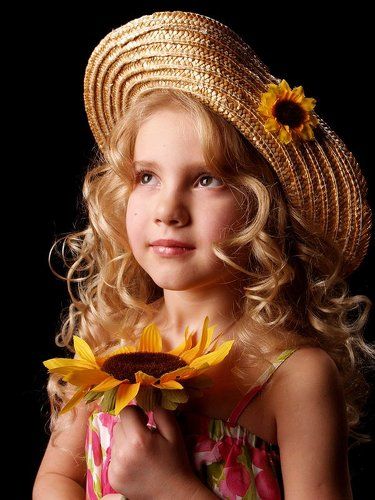 Портрет маленькой девочки с подсолнухом в руках и в соломенной шляпке.