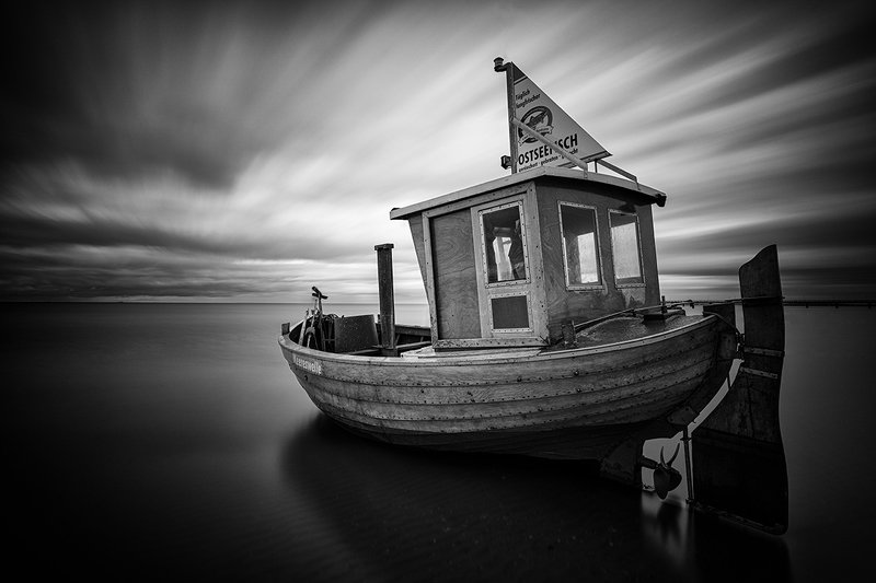 fishing boat, sea, black and white, sky, clouds, long exposure Abandoned fishing boat on the sea shorephoto preview