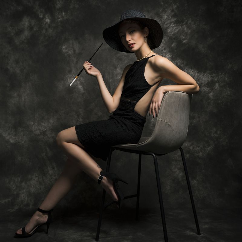 beautiful woman, beauty, cigarette, dress, elegance, fashion, female, grace, hat, high heels, individuality, indoors, looking at camera, necklace, one person, portrait, retro, sensuality, side view, sitting, stool, studio shot, vintage, young women Girl With a Cigarettephoto preview