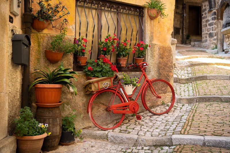 борго, город, италия, велосипед, цветы, герани, красный Красный велосипед и красные герани в итальянском борго Castro del Volsci в Италииphoto preview