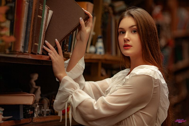 Young woman reading book in libraryphoto preview