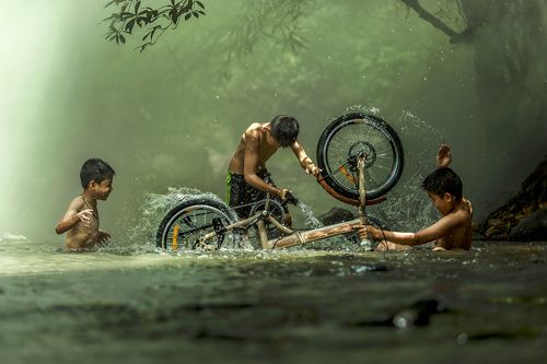 The boys are washing bicycle playfully River Near Home